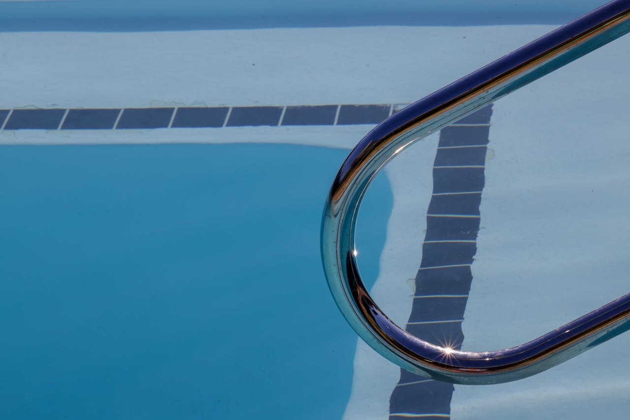 about-01 Dynamic view of a swimming pool with ladder reflecting sunlight on the water surface.